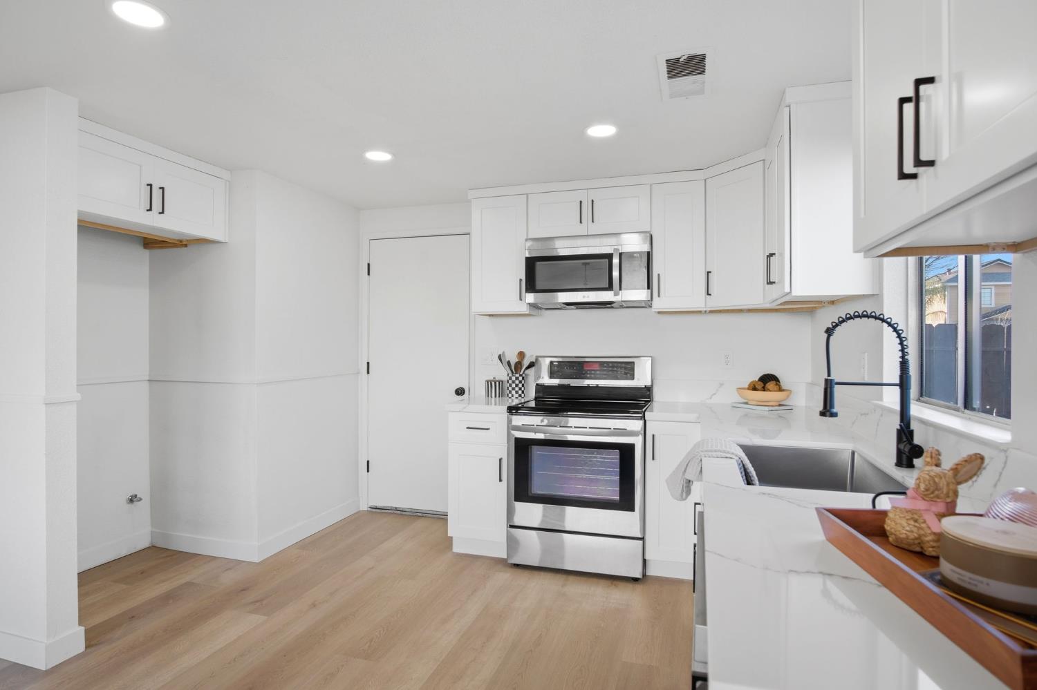 1732 Walpole Drive Modesto, CA 95358 - Photo 8 of 21 a kitchen with stainless steel appliances a stove a sink a refrigerator white cabinets and a wooden floor