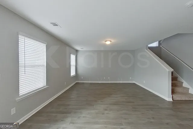 an empty room with wooden floor and windows