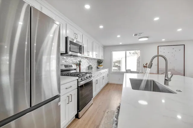 a kitchen with stainless steel appliances granite countertop a refrigerator sink and stove
