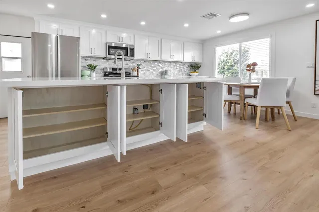 a kitchen with stainless steel appliances kitchen island granite countertop a stove top oven a sink and a refrigerator