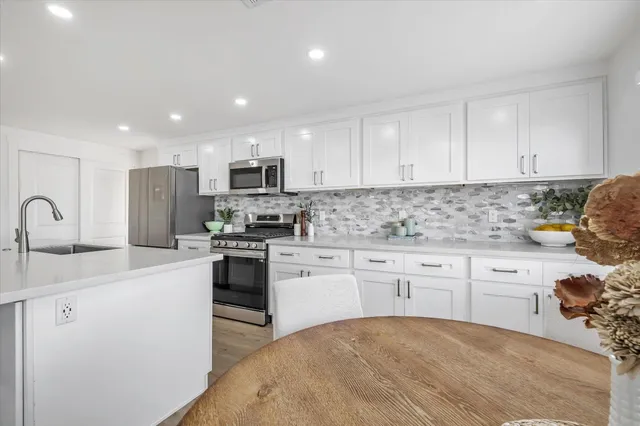 a kitchen with granite countertop white cabinets and stainless steel appliances