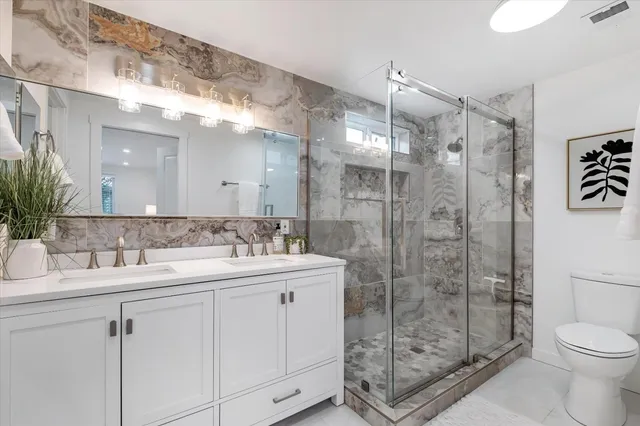 a bathroom with a double vanity sink toilet and shower