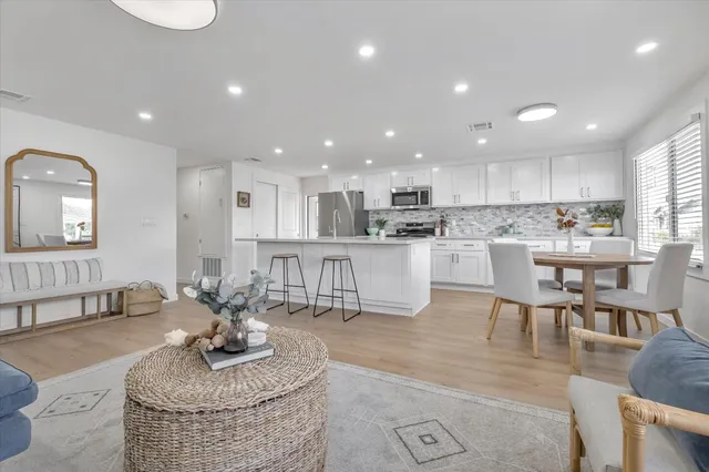 a living room with stainless steel appliances furniture dining table and kitchen view