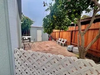 a view of a backyard with table and chairs potted plants and wooden fence