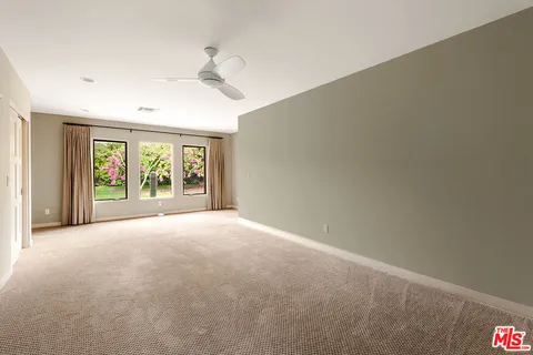 an empty room with windows and chandelier fan