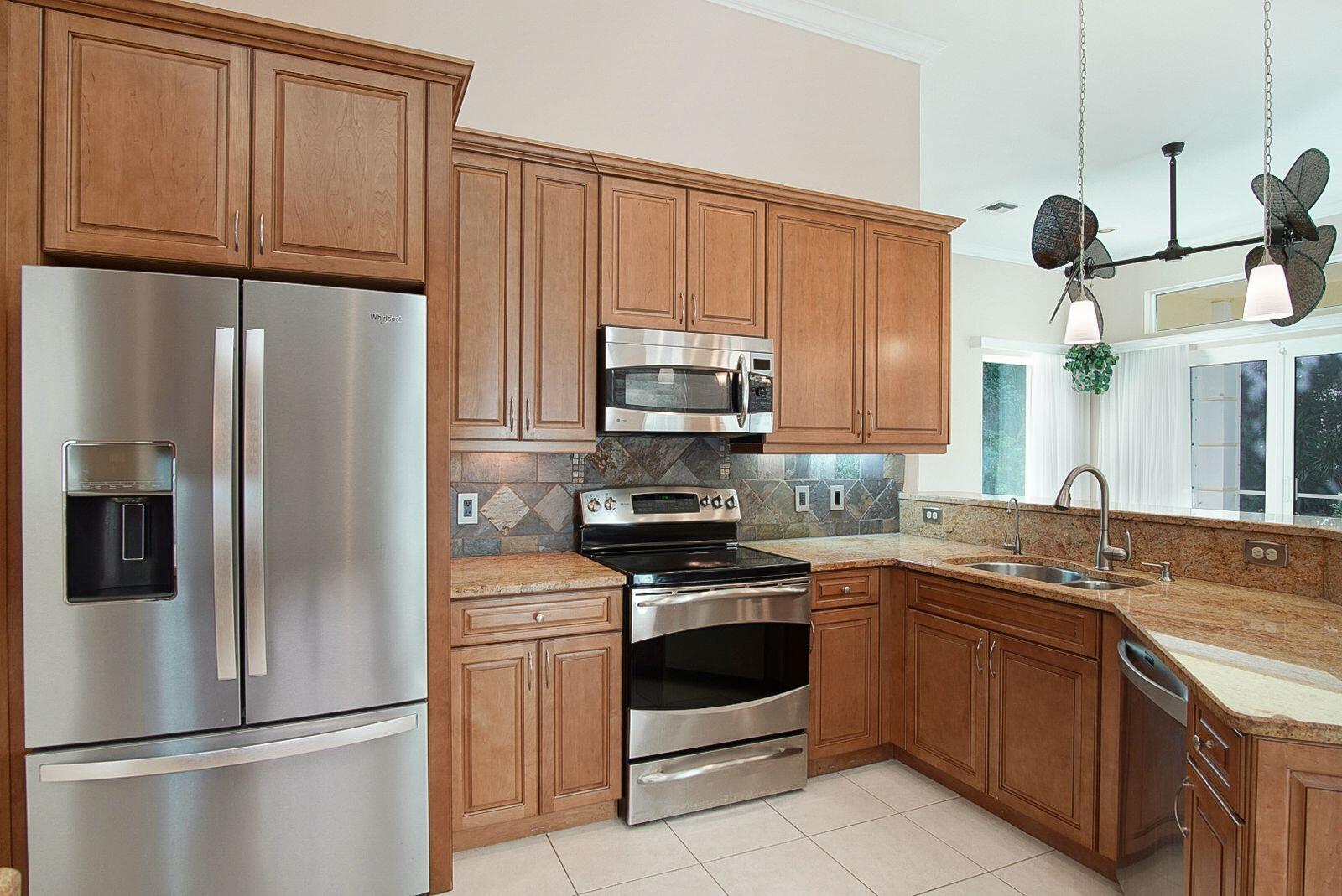 5496 Southeast Reef Way Stuart, FL 34997 - Photo 13 of 35 a kitchen with stainless steel appliances granite countertop a refrigerator a stove and a sink with cabinets