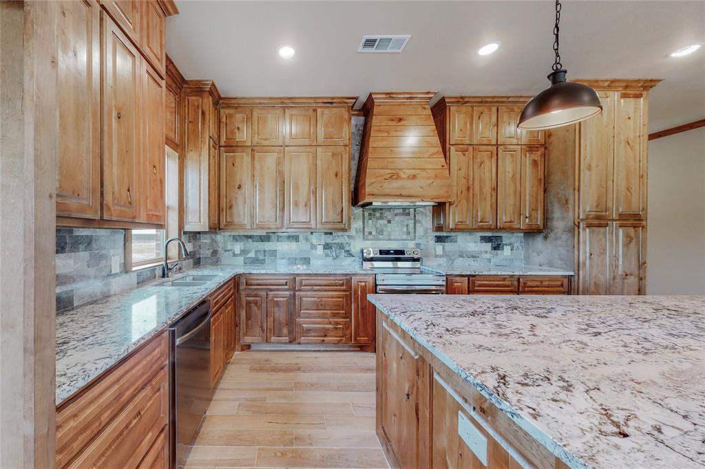 a kitchen with stainless steel appliances granite countertop a sink a stove and a wooden cabinets