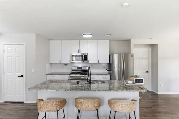 a kitchen with stainless steel appliances granite countertop a kitchen island a chairs a sink and a refrigerator