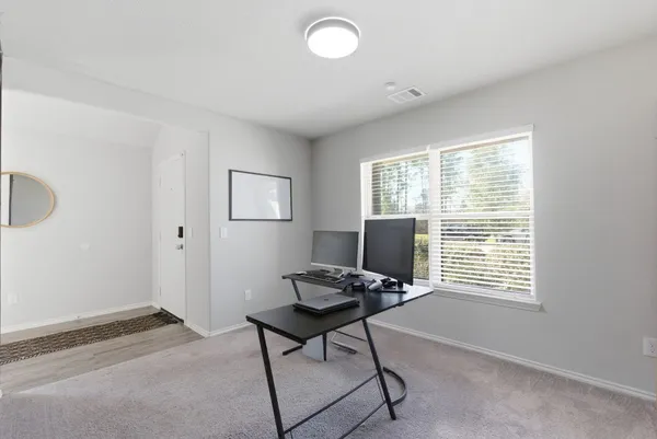a view of a workspace with furniture and a window