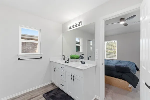 a en suite bathroom with a double vanity sink a window and mirror