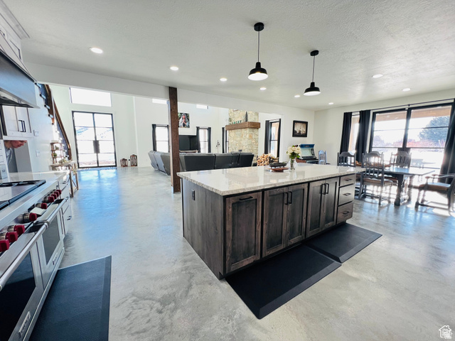 100 Whit Lane Georgetown, ID 83239 - Photo 76 of 76 Kitchen featuring open floor plan, a kitchen island, light stone countertops, finished concrete flooring, and a textured ceiling