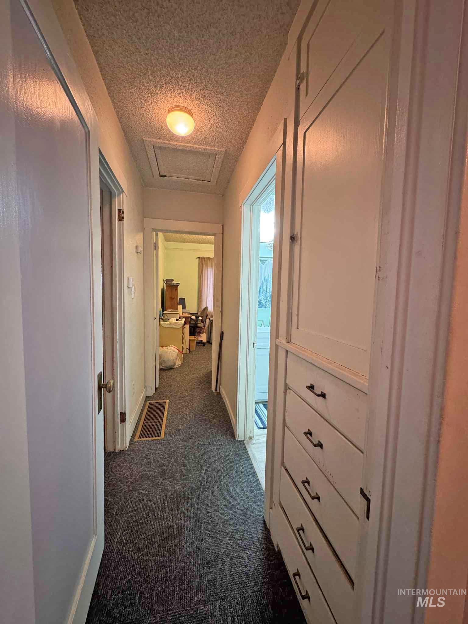318 Maple Street Clarkston, WA 99403 - Photo 9 of 14 Hall with dark carpet, a textured ceiling, and attic access
