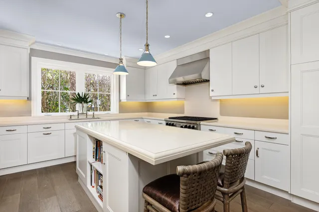 a kitchen with stainless steel appliances kitchen island granite countertop a table chairs and a sink