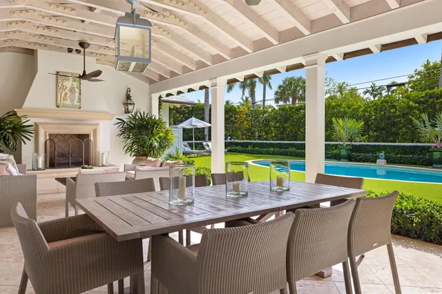 a view of a swimming pool with a table and chairs under palm trees