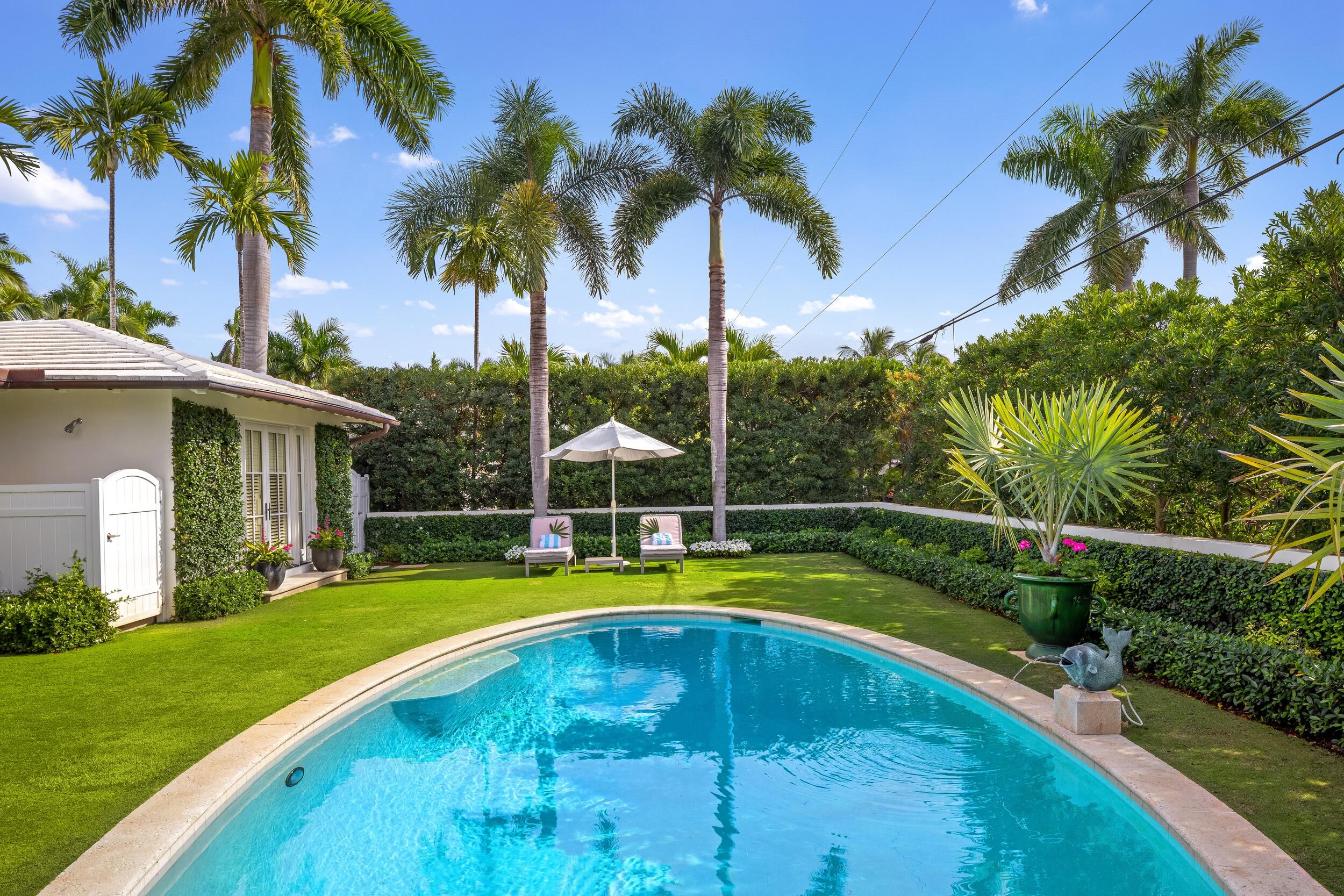 258 List Road Palm Beach, FL 33480 - Photo 45 of 49 a view of a swimming pool with a table and chairs under palm trees