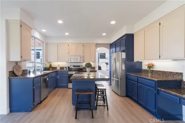 a kitchen with stainless steel appliances granite countertop sink refrigerator dining table and chairs