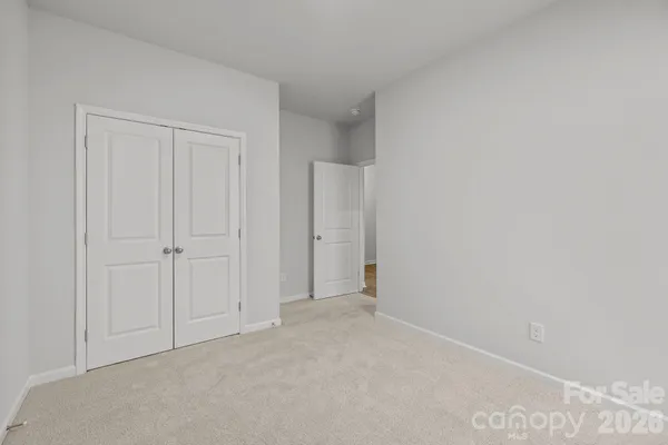 a view of an empty room with kitchen and window