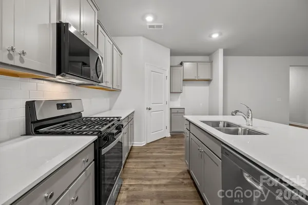 an empty room with wooden floor chandelier and windows