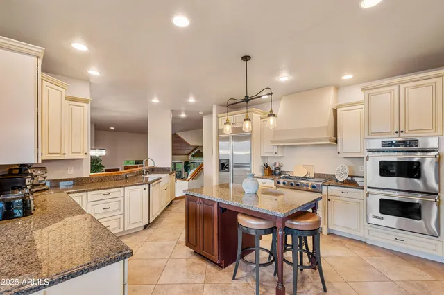 a large kitchen with granite countertop lots of counter top space and stainless steel appliances