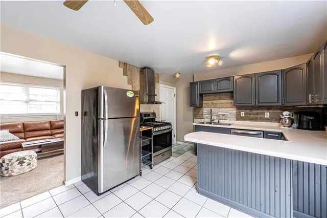 a kitchen with stainless steel appliances granite countertop a refrigerator a stove and a sink with large windows