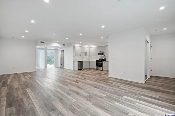 a kitchen with cabinets stainless steel appliances and wooden floor