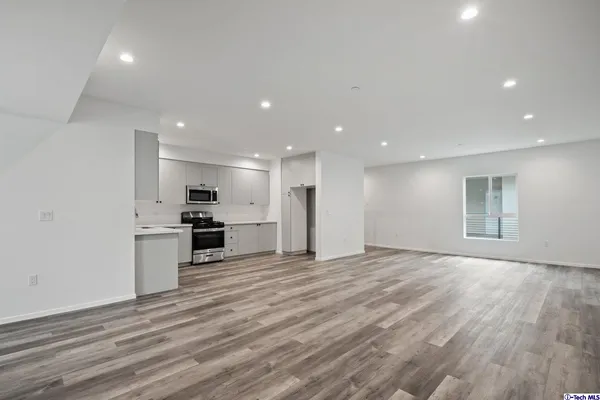 a view of an empty room with wooden floor and closet