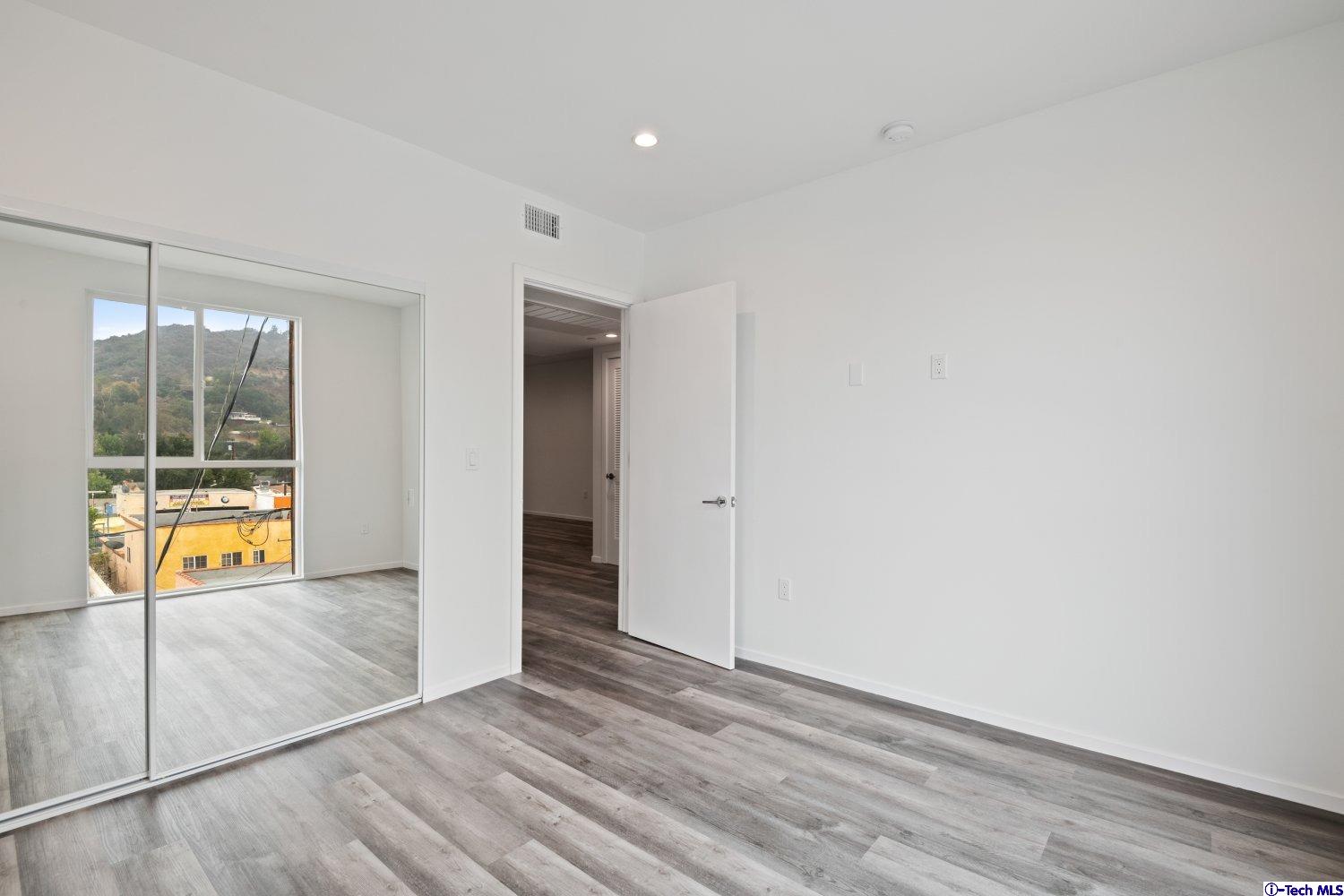 7064 Greeley Street, Unit 204 Tujunga, CA 91042 - Photo 29 of 39 an empty room with wooden floor and windows