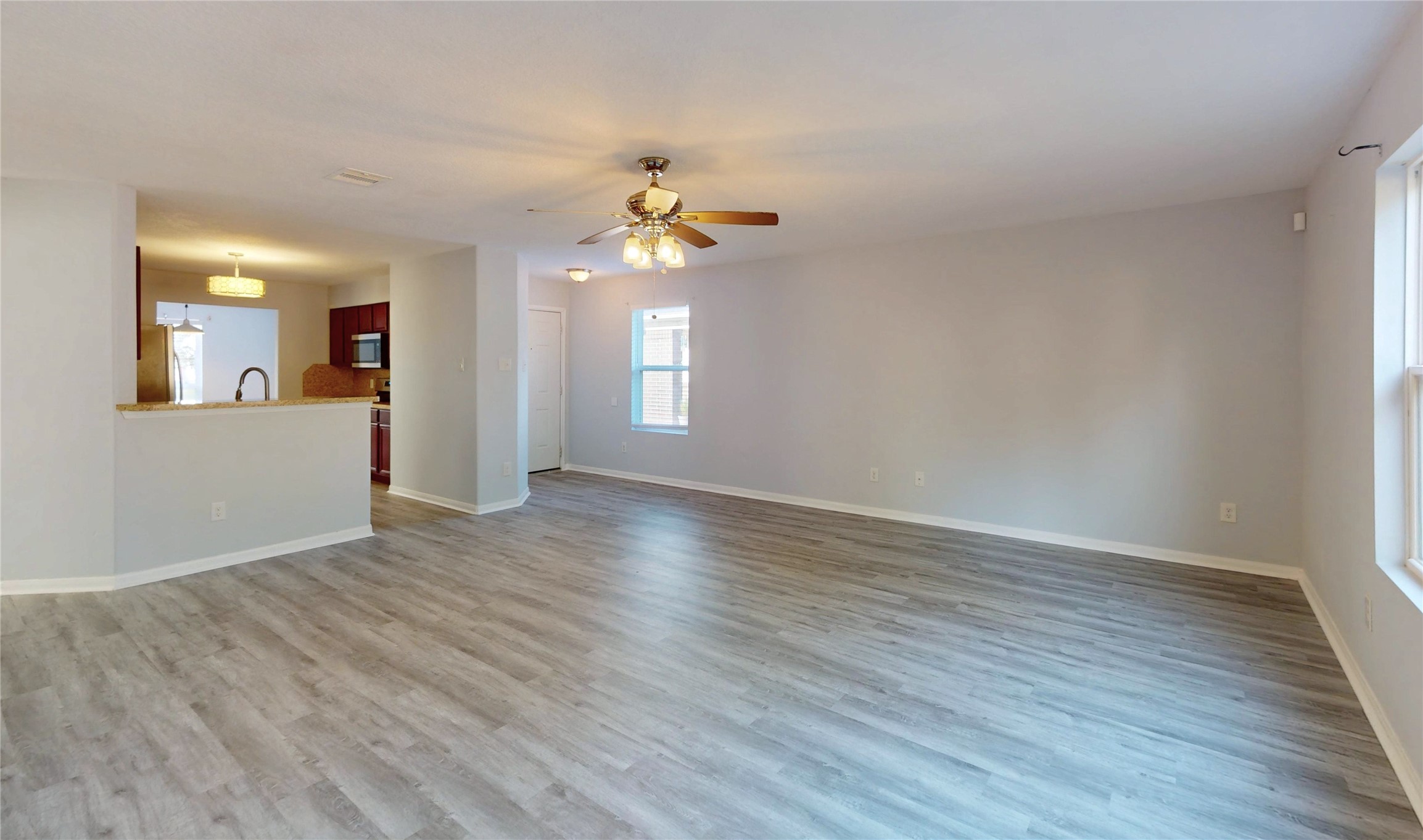 9877 Lace Flower Way Conroe, TX 77385 - Photo 8 of 43 an empty room with wooden floor chandelier fan and windows
