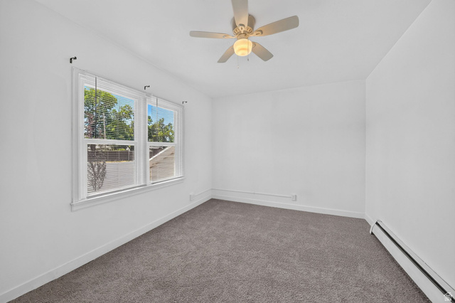 220 East Greenwood Avenue Midvale, UT 84047 - Photo 20 of 46 Bright room featuring a multi-pane window with blinds, a ceiling fan with integrated lighting, and plush grey carpeting