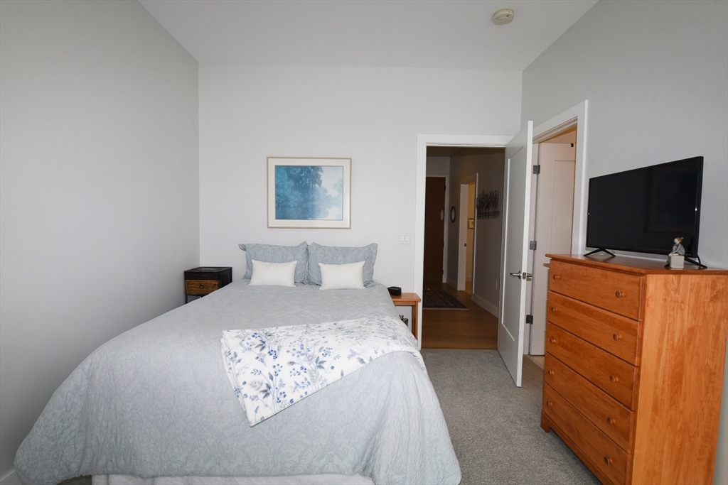 10 Shipyard Drive, Unit 313 Hingham, MA 02043 - Photo 22 of 39 a bedroom with a bed and a flat tv screen on wall