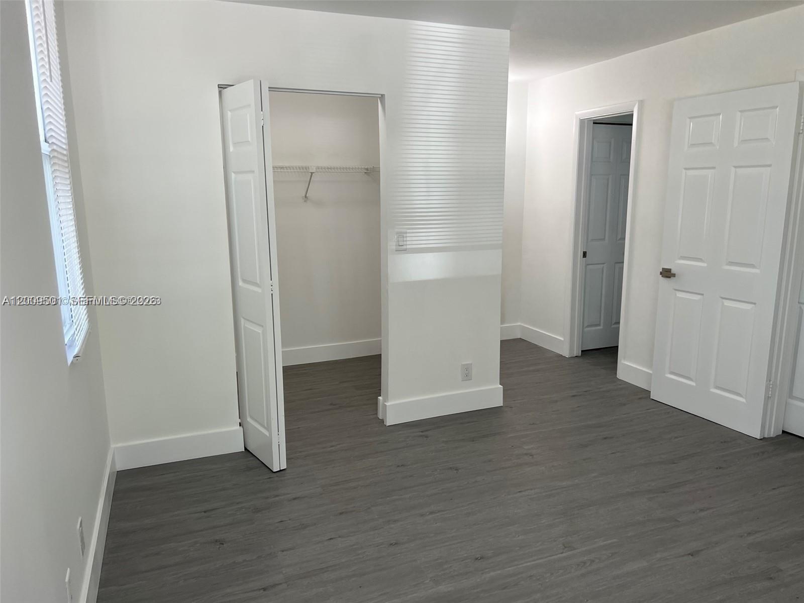 931 Lyons Road, Unit 4101 Coconut Creek, FL 33063 - Photo 6 of 23 an empty room with wooden floor & closet area
