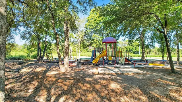 a view of a park with large trees and a barn