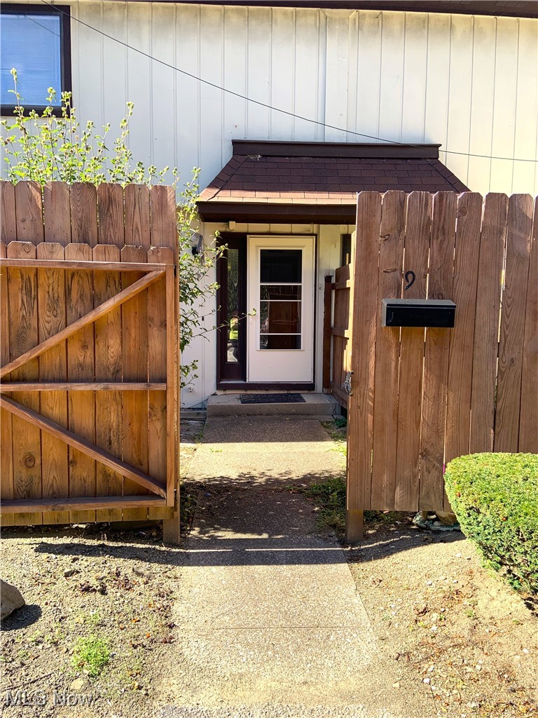 9956 Johnnycake Ridge Road, Unit D9 Painesville, OH 44077 - Photo 20 of 37 Doorway to property with a gate, roof with shingles, and board and batten siding