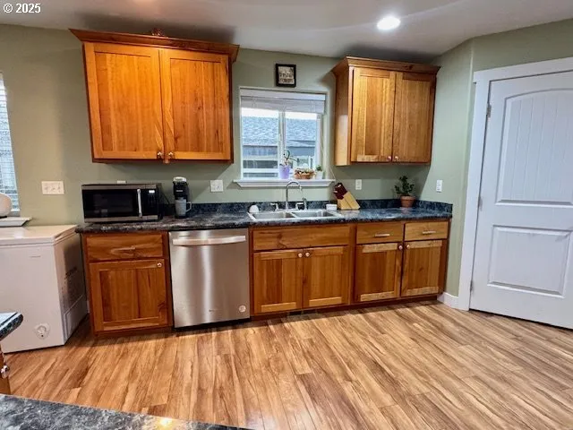 a kitchen with stainless steel appliances granite countertop wooden cabinets a sink and dishwasher with wooden floor