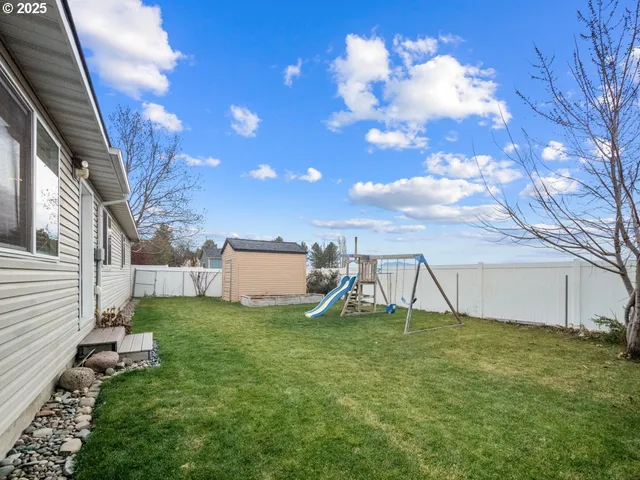 a backyard of a house with childrens swings and slides