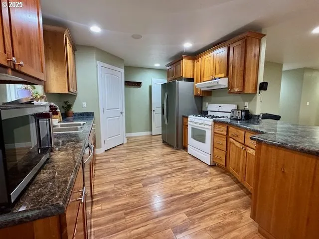 a kitchen with stainless steel appliances granite countertop wooden cabinets a stove top oven a sink and dishwasher