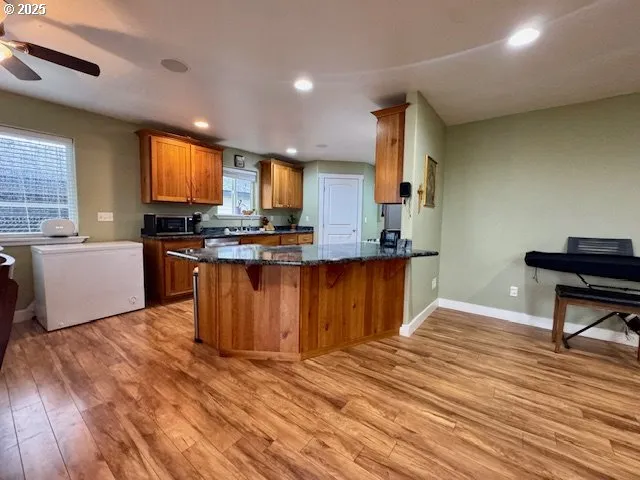 a kitchen with kitchen island granite countertop wooden floors and a sink