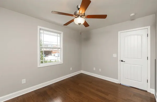 an empty room with wooden floor chandelier fan and windows
