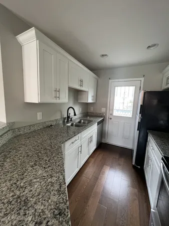 a kitchen with granite countertop a sink a window appliances and cabinets