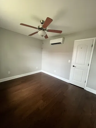 an empty room with wooden floor fan and windows