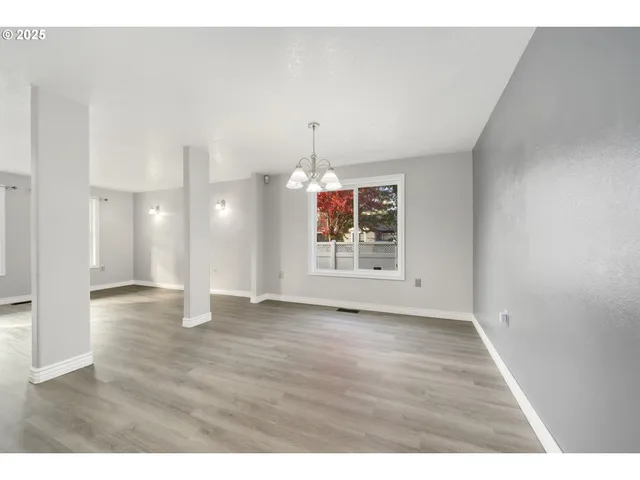 a view of an empty room with window and wooden floor