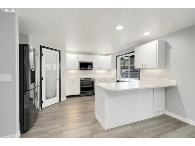 a kitchen with stainless steel appliances a sink a stove a refrigerator and cabinets