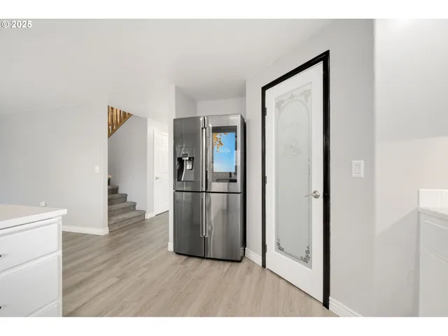 a hallway with wooden floor electronic appliances and stairs