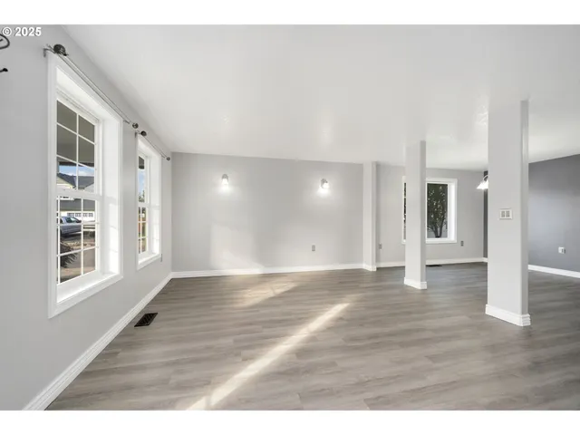 a view of an empty room with window and wooden floor