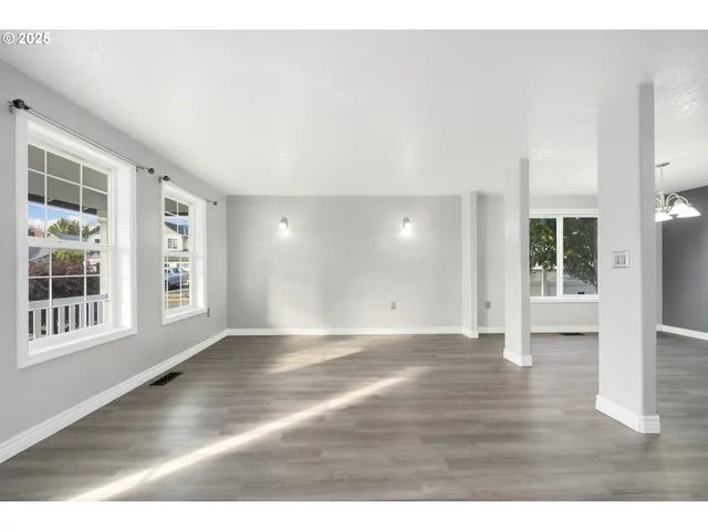 a view of an empty room with wooden floor and windows