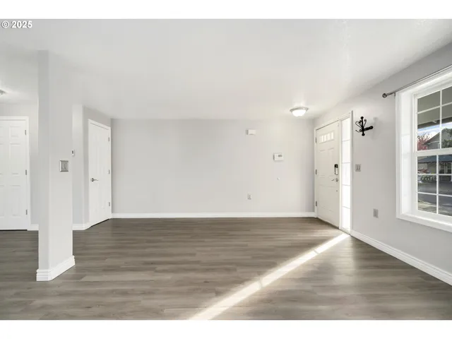 a view of an empty room with wooden floor and windows