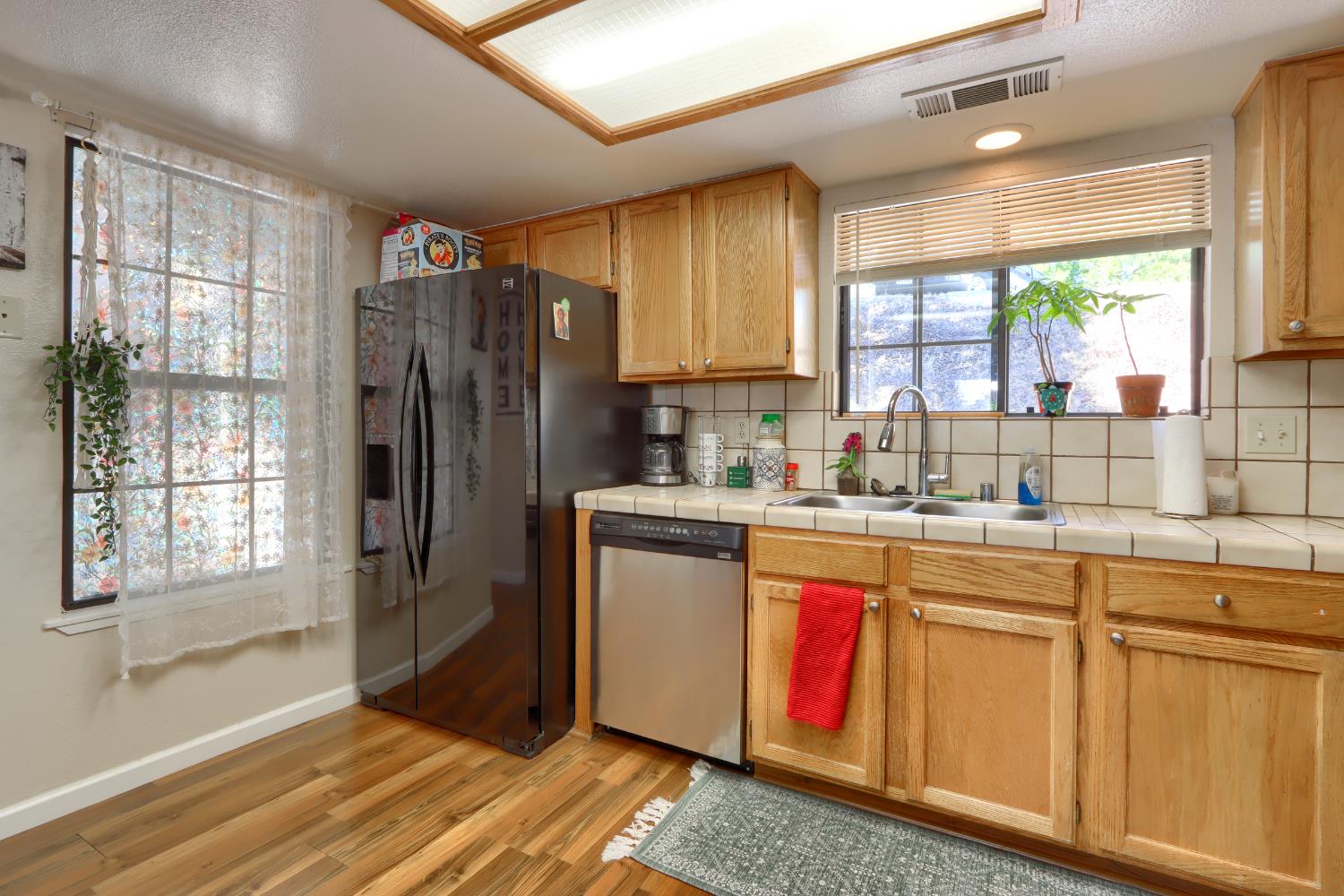 50840 Smoke Tree Trail Bass Lake, CA 93604 - Photo 17 of 43 a kitchen with stainless steel appliances granite countertop a refrigerator a sink dishwasher a stove a dining table and chairs with wooden floor