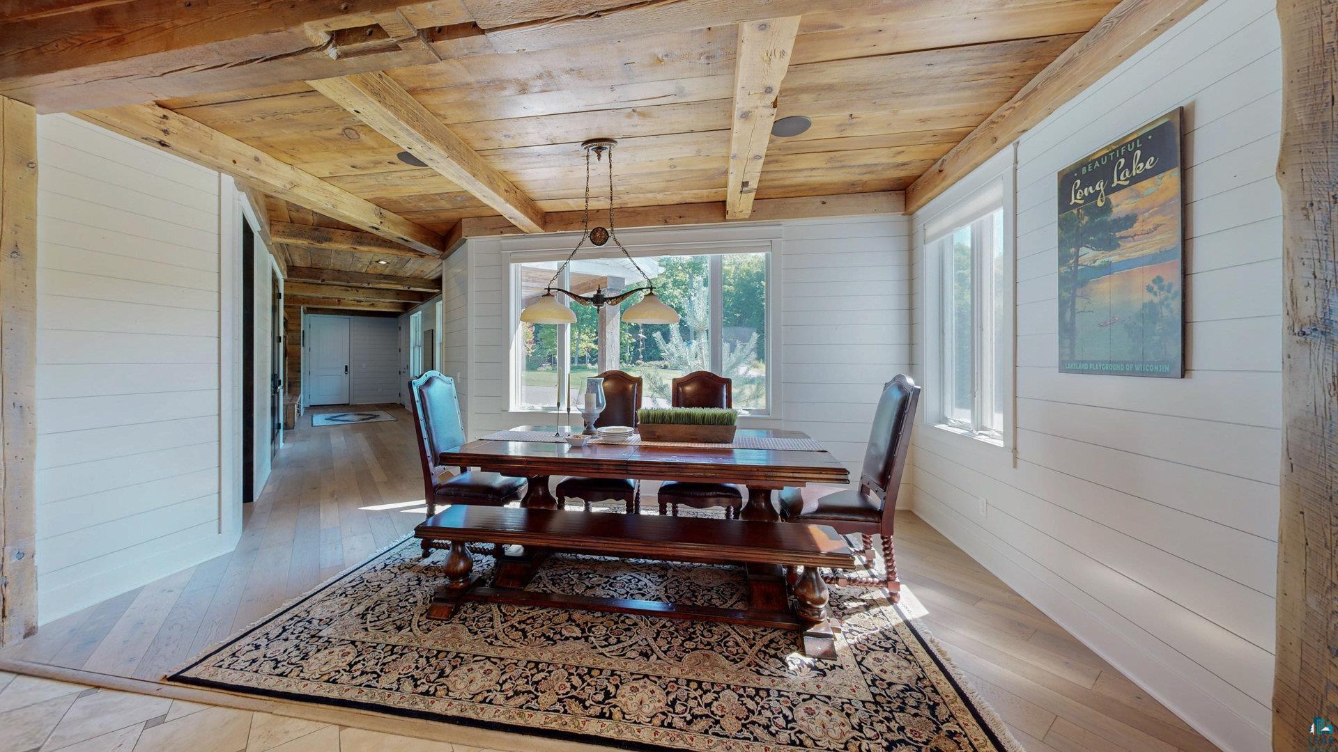 N1211 East Side Road Birchwood, WI 54817 - Photo 18 of 70 Dining space with wood walls, a wooden ceiling with exposed beams, and light wood-style floors