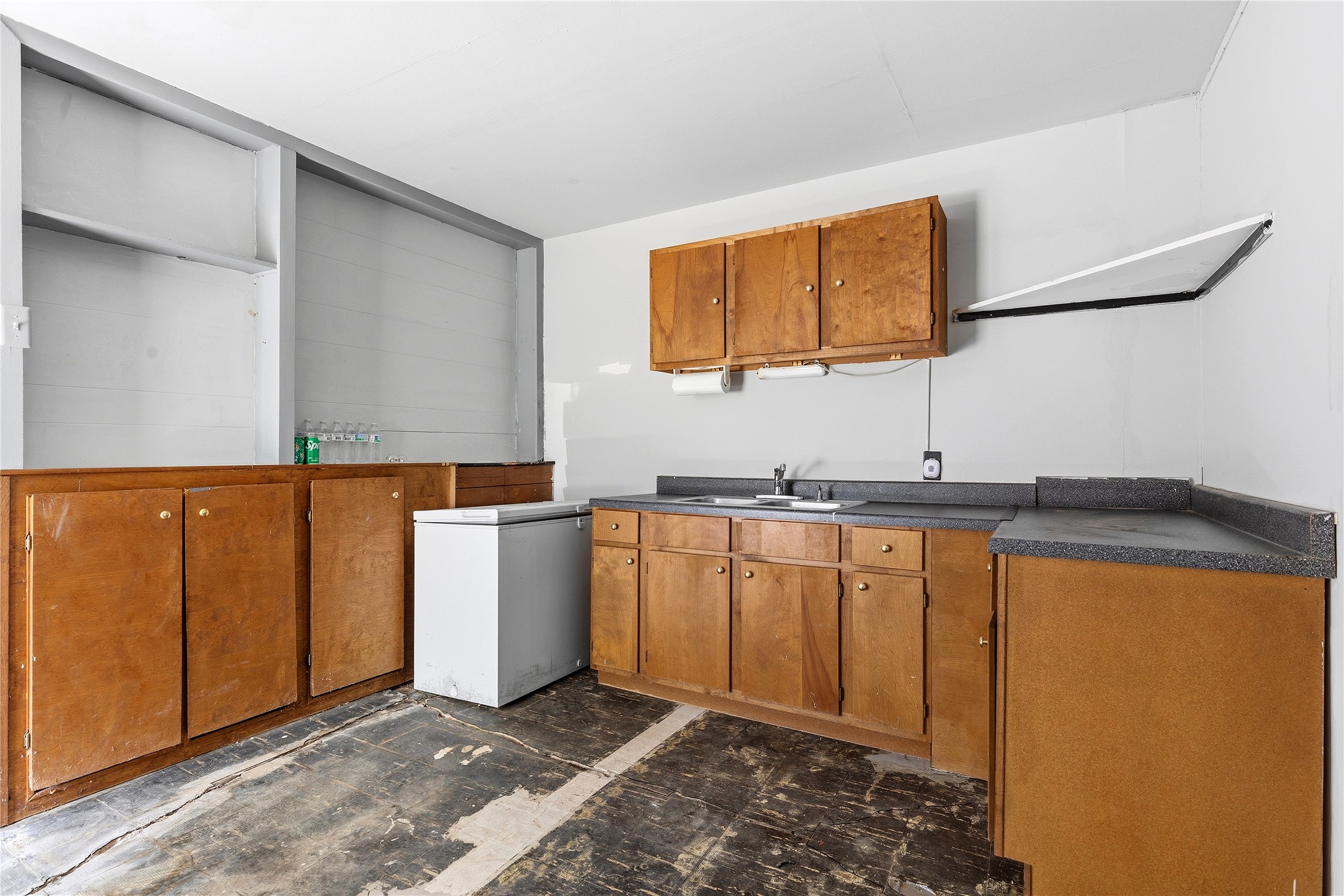 4900 Duval Street Austin, TX 78751 - Photo 22 of 25 Attached apartment kitchen area with existing cabinetry, sink, and access to a full bath with shower. This space offers renovation potential, with visible condition concerns including uneven flooring; buyer should independently evaluate foundation, structure, and overall condition.