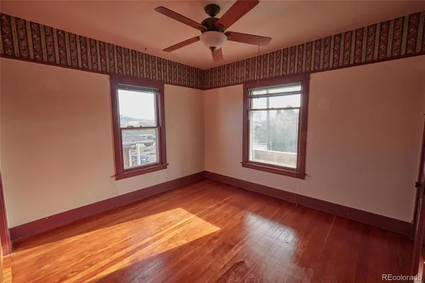 a view of an empty room with a window and wooden floor